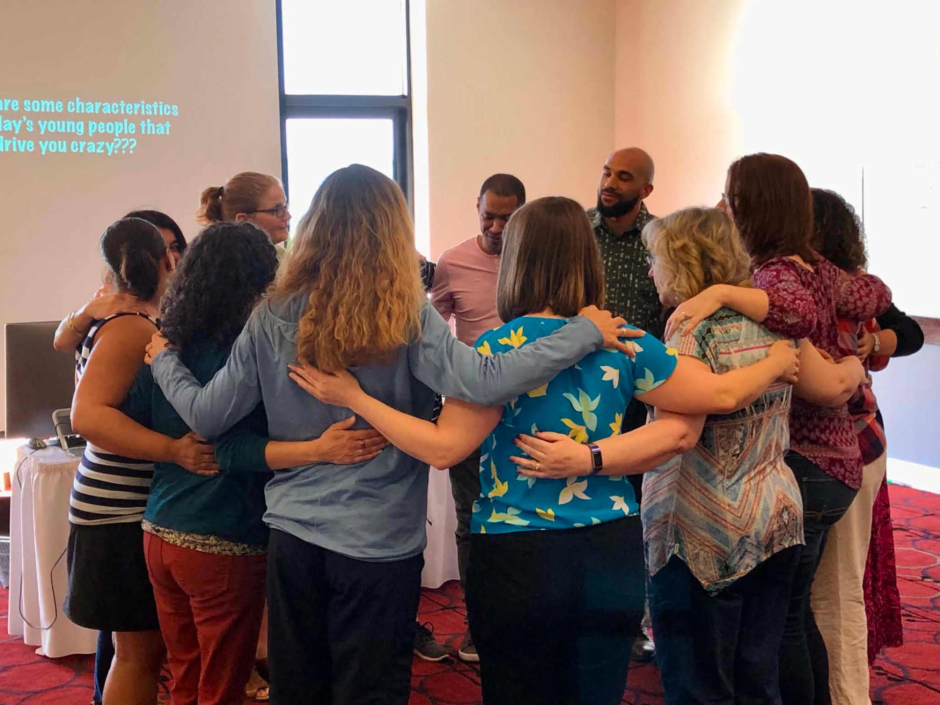 Academy participants standing arm in arm in a circle during a session activity