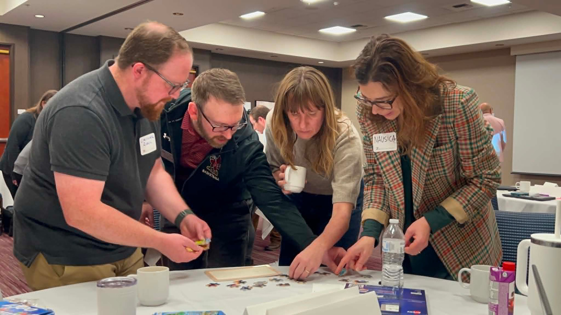 Four Academy participants leaning over a table working together on a hands-on exercise
